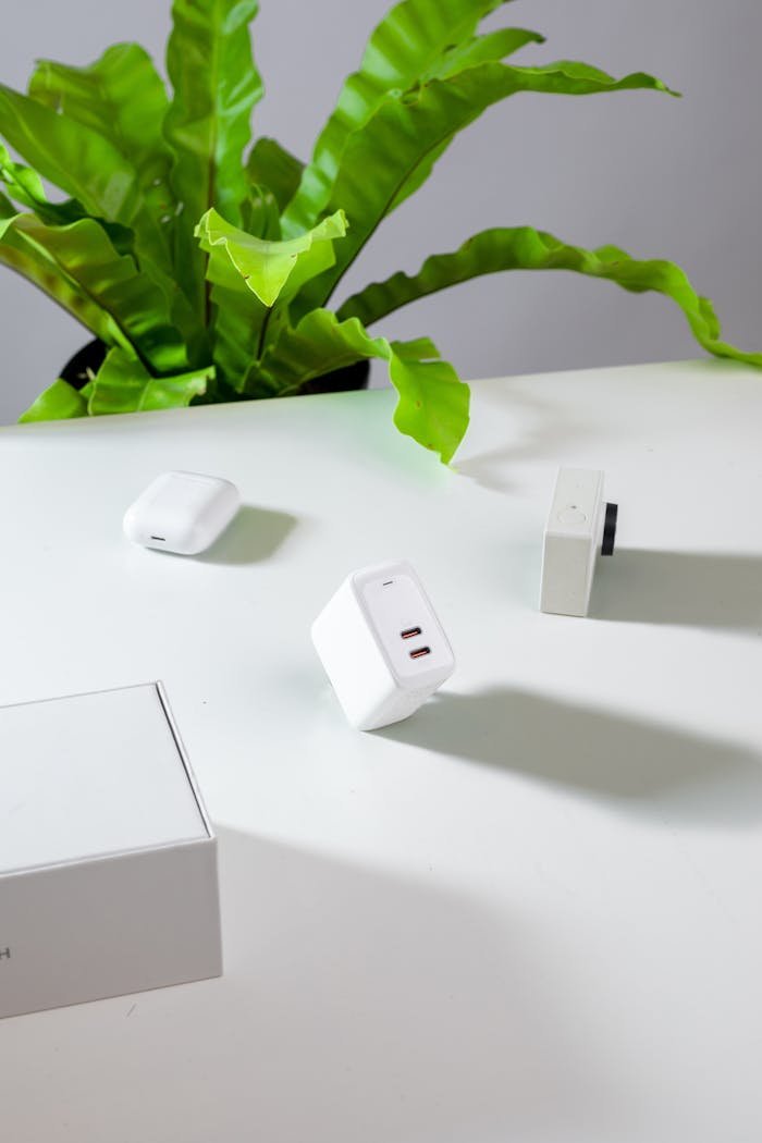 A clean and modern workspace featuring a plant and electronic devices on a white desk.
